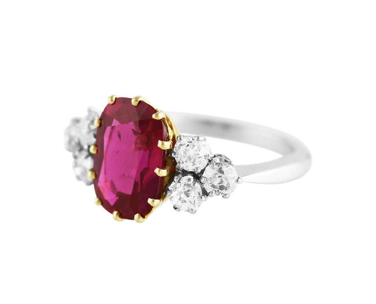This stunning platinum, 18 karat yellow gold, ruby and diamond ring is set in the center with an oval ruby weighing 3.70 carats, flanked by 6 old European-cut diamonds weighing approximately 0.90 carat, size 6 3/4, gross weight 6.0 grams, measuring