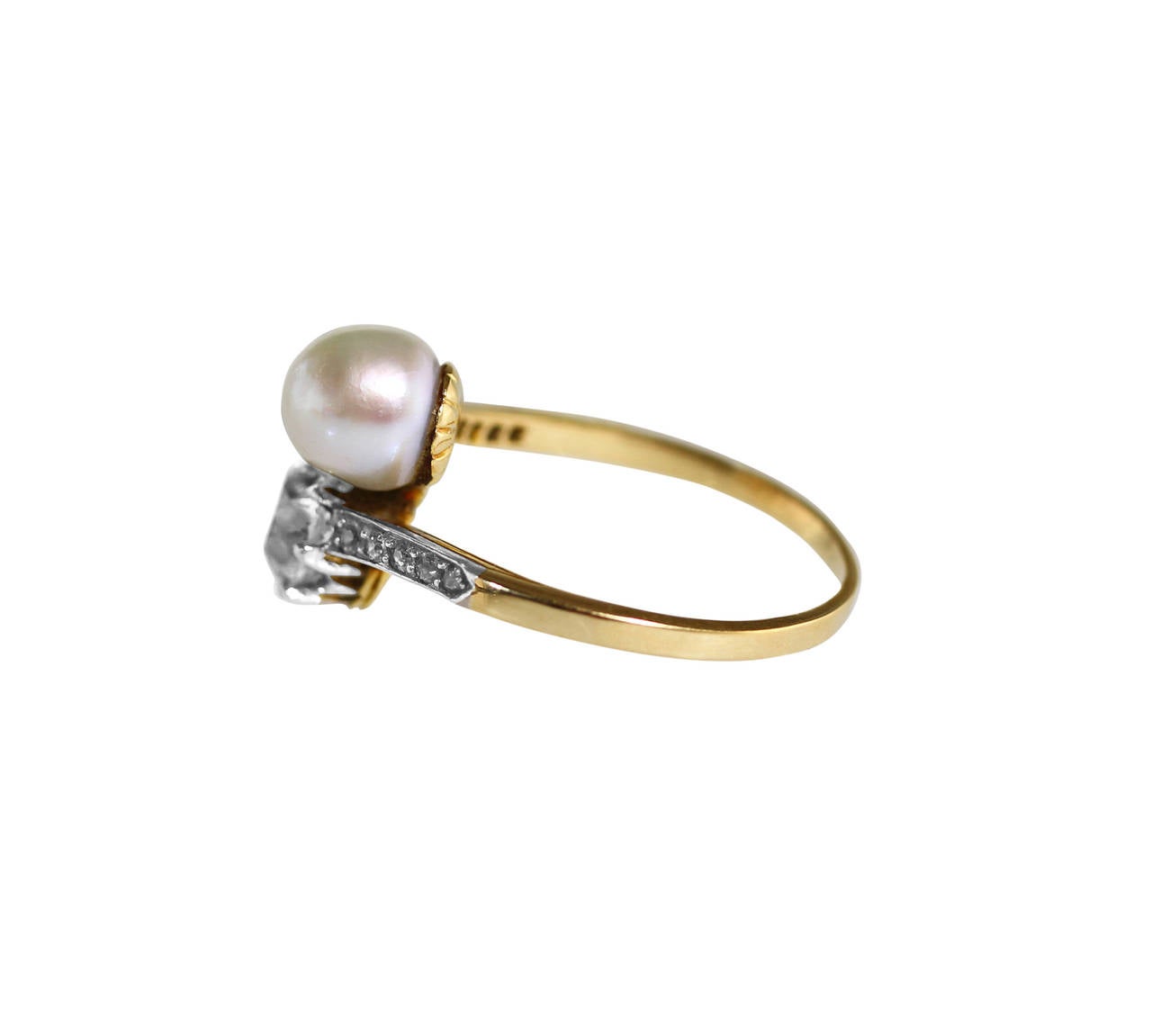 An Early 20th Century 18 karat yellow gold, platinum, natural pearl and diamond ring, circa 1905, of crossover design set with a natural pearl measuring approximately 6.9 by 6.8 mm., and an old European-cut diamond weighing 1.30 carats, flanked by