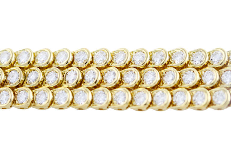 This classic looking 18 karat yellow gold and diamond bracelet was made by Van Cleef & Arpels, France. The bracelet is designed as a highly flexible strap of three rows set with 129 round diamonds weighing 14.12 carats, gross weight 43.8 grams,