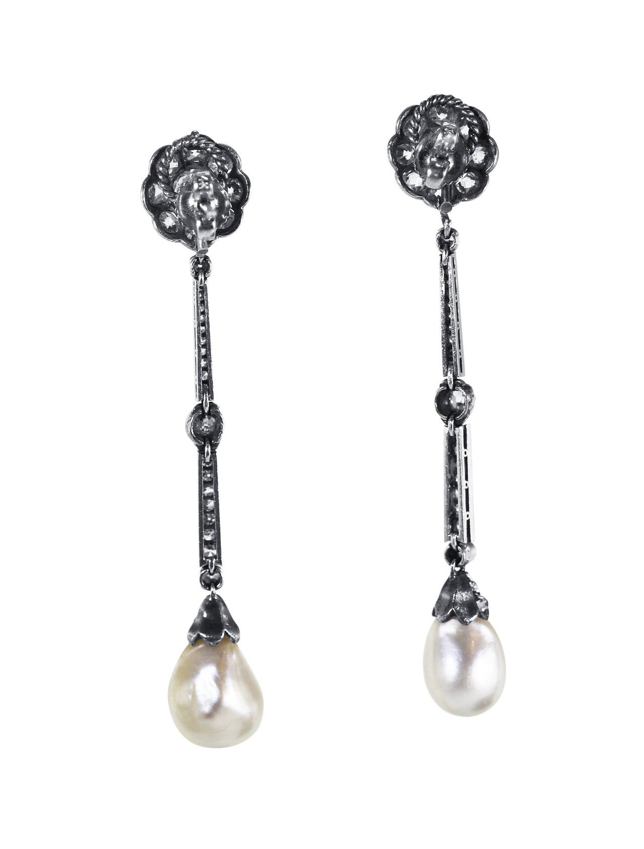 A pair of silver, platinum, natural pearl and diamond pendant-earrings, the pendants set with 2 semi-baroque natural pearl drops measuring 10.01 by 8.90 mm. and 9.23 by 8.58 mm., supported by articulated graduated pendants set throughout with 2 old