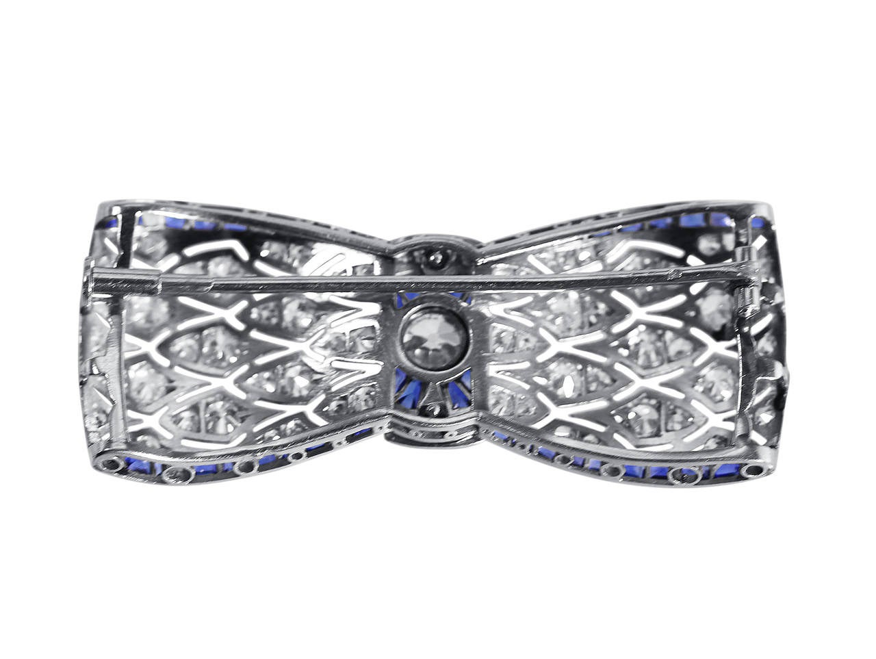 An Art Deco platinum, sapphire and diamond brooch, circa 1925, designed as a openwork bow set in the center with an old European-cut diamond weighing approximately 0.50 carat, further set with 70 old European-cut and single-cut diamonds weighing