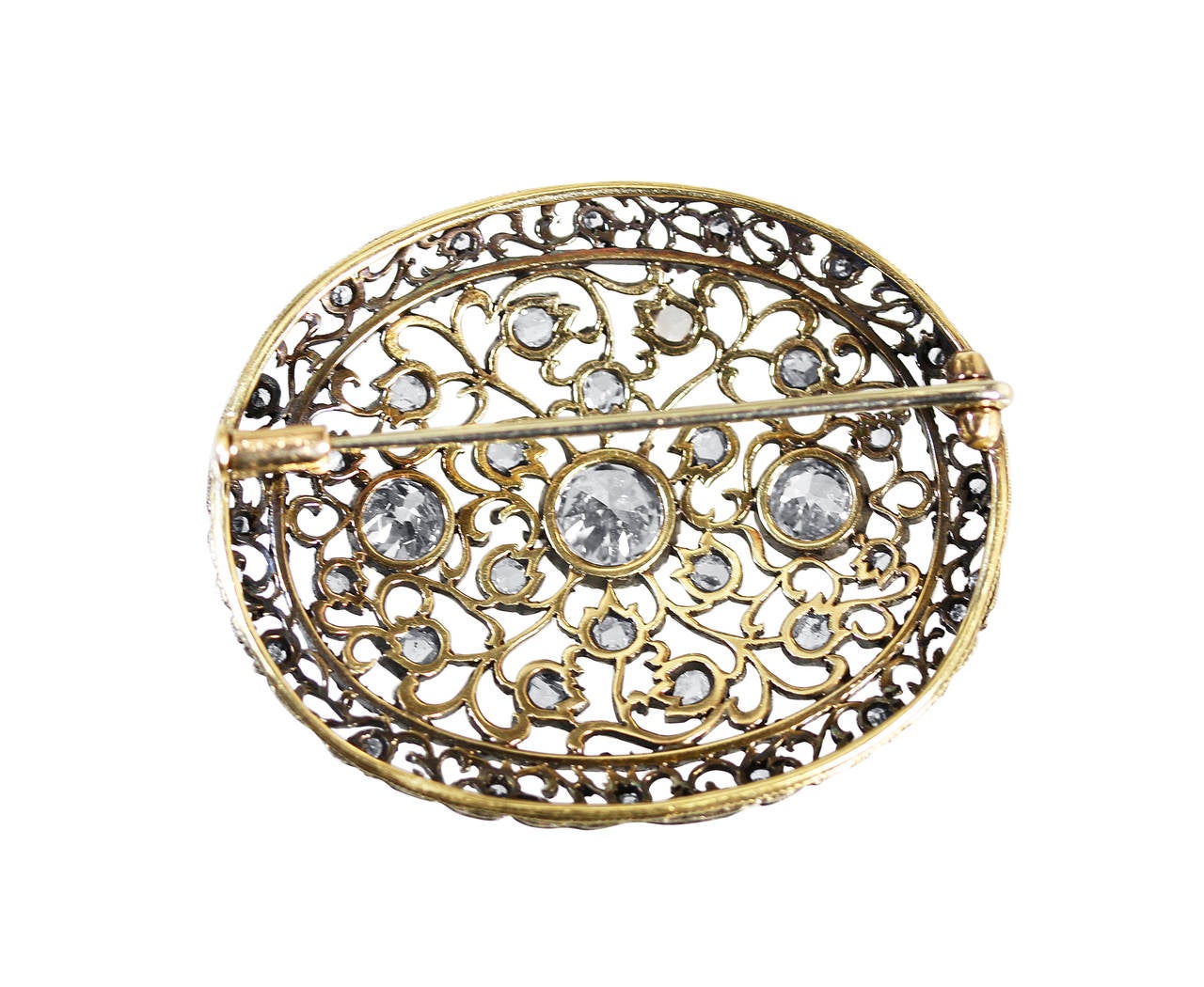 An antique silver, 18 karat yellow gold and diamond brooch by Mario Buccellati, Italy, circa 1930, the oval brooch of openwork floral design set in the center with 3 round and old European-cut diamonds weighing approximately 1.50 carats, further set