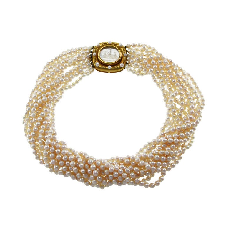 An 18 karat yellow gold, cultured pearl and glass intaglio necklace by Elizabeth Locke, the torsade composed of 12 strands of numerous high luster cultured pearls measuring approximately 4.7 mm., completed by a gold clasp set in the center with an