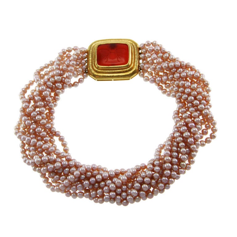 An 18 karat yellow gold, cultured pearl and carnelian intaglio necklace by Elizabeth Locke, the torsade composed of 10 strands of high luster pink cultured pearls measuring approximately 5.0 mm., completed by a rectangular stippled gold clasp set in