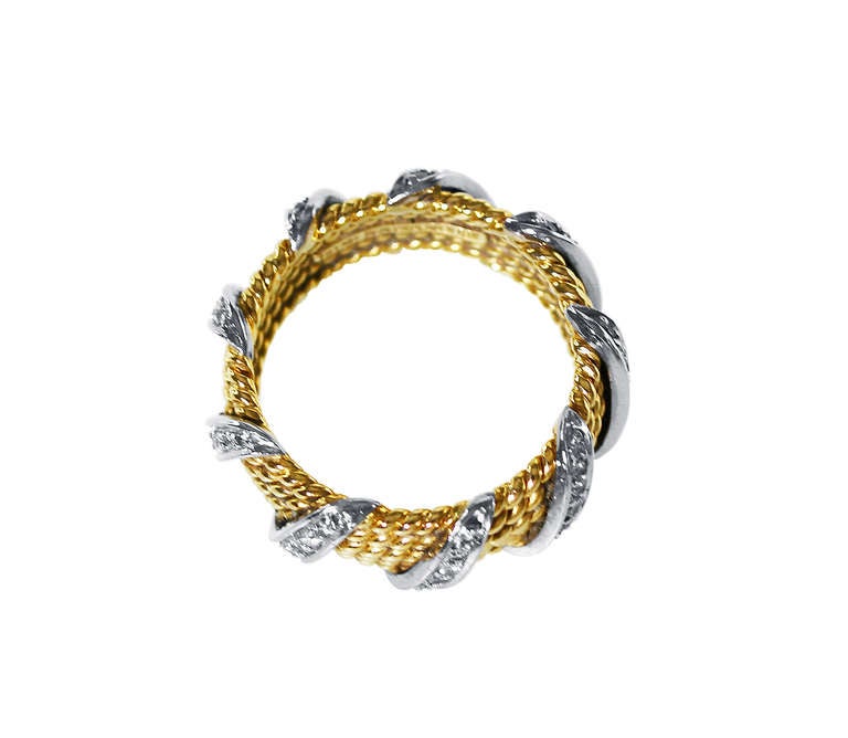 An 18 karat yellow gold and diamond band ring by Schlumberger for Tiffany & Co., designed as a five-row ropetwist gold band accented by white gold diagonal bands set with 63 round diamonds weighing approximately 1.00 carat, size 8 3/4, gross weight
