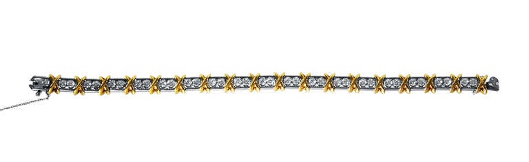 An 18 karat yellow gold, platinum and diamond 36 Stone bracelet by Schlumberger for Tiffany & Co., designed as a series of polished gold 'x' shaped links spaced by 36 round diamonds weighing a total of approximately 2.95 carats, gross weight 38.9