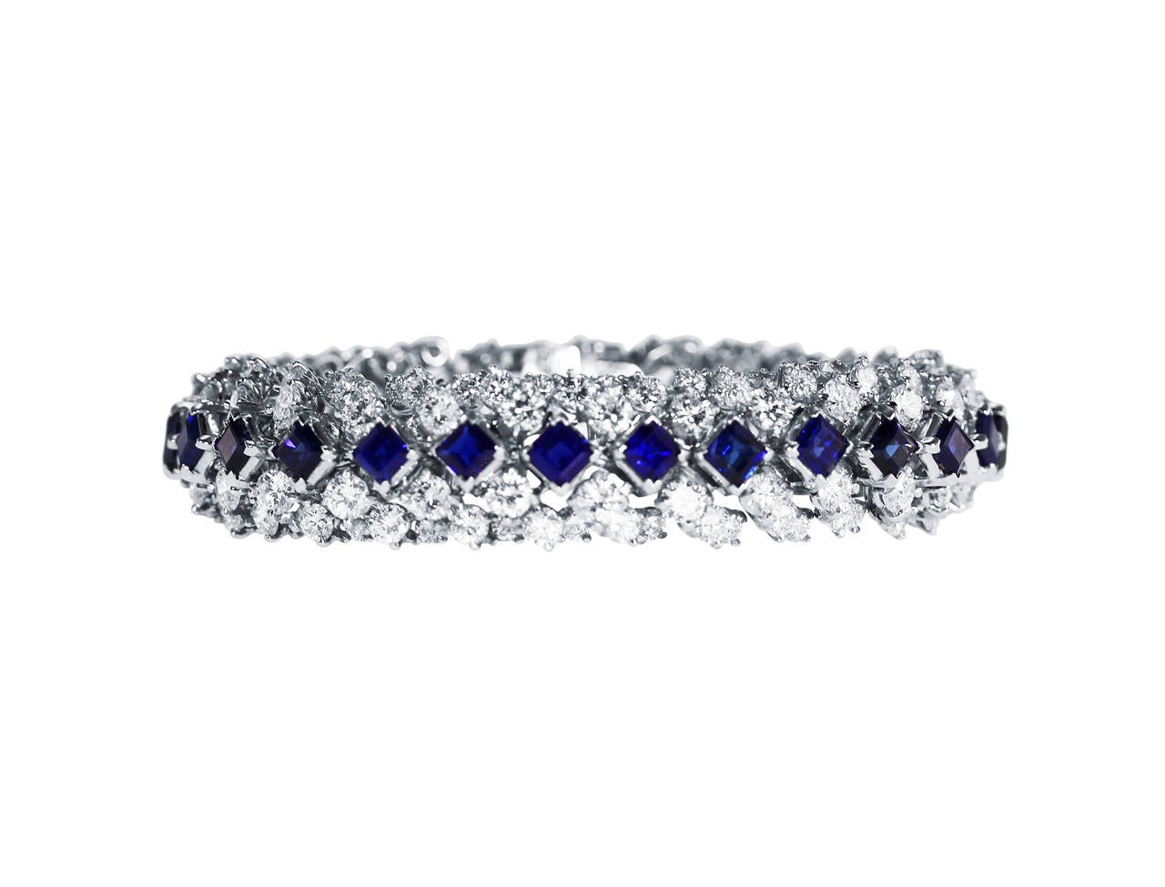 This stunning an highly flexible platinum, sapphire and diamond bracelet is by Oscar Heyman & Brothers, circa 1965, the highly articulated strap set down the center with 27 square-cut sapphires weighing 18.96 carats, flanked on either side with 162