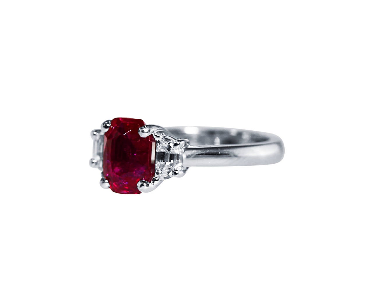 A platinum, ruby and diamond ring, set in the center with cushion-shaped ruby weighing 2.34 carats, flanked by 2 half-moon-shaped diamonds weighing approximately 0.50 carat, gross weight 7.2 grams, size 6, measuring 7/8 by 1 by 3/8