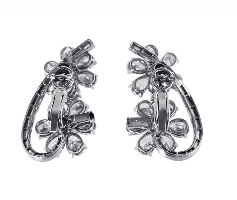 A pair of platinum and diamond earclips of floral design set throughout with 4 large round, 26 baguette and 24 large pear-shaped diamonds weighing approximately 13.50 carats, gross weight 20.3 grams, measuring 1 1/4 by 5/8 inches.  A stunning pair