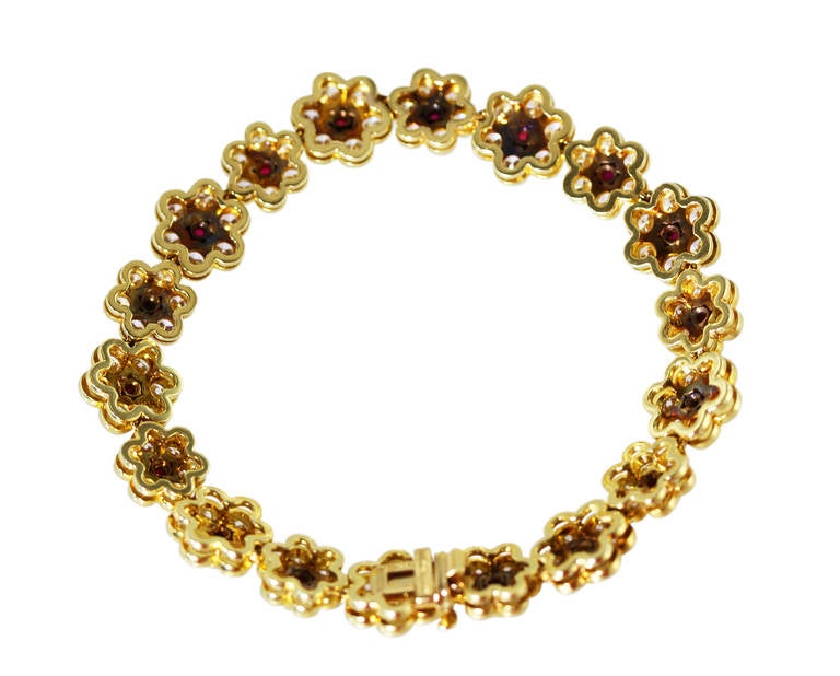 An 18 karat yellow gold, ruby and diamond bracelet by Van Cleef & Arpels, New York, designed as a line of flowerheads set with 18 round rubies weighing approximately 3.00 carats, and 108 round diamonds weighing approximately 8.00 carats, gross