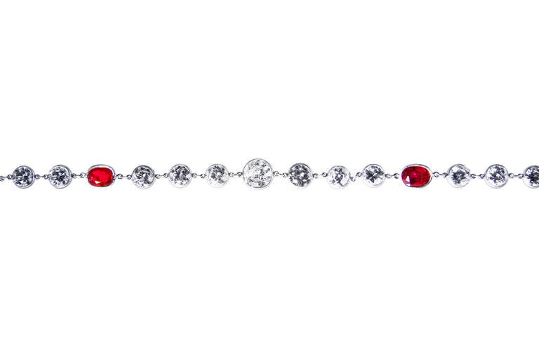 A stunning platinum, ruby and diamond long chain, collet-set with 14 oval rubies weighing 12.54 carats, accented by 92 collet-set round diamonds weighing 23.65 carats, gross weight 27.5 grams, length 33 3/4 inches, width 1/4 inch, clasp stamped