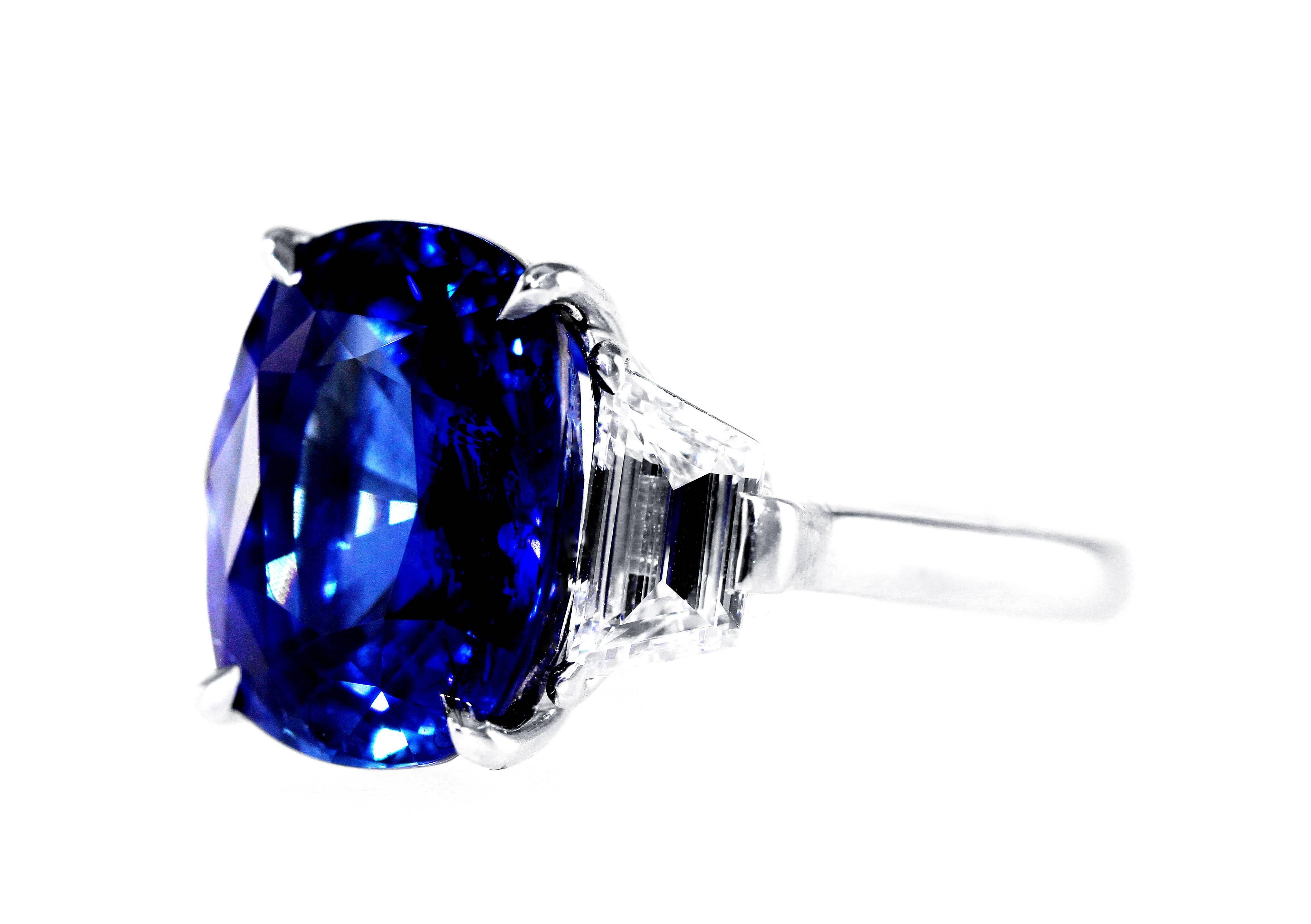 A superb platinum, sapphire and diamond ring, set in the center with an oval sapphire weighing 12.65 carats, flanked by 2 trapeze-cut diamonds weighing approximately 1.60 carats, gross weight 11.2 grams, measuring 3/4 by 5/8 by 1 1/8 inches, size 6
