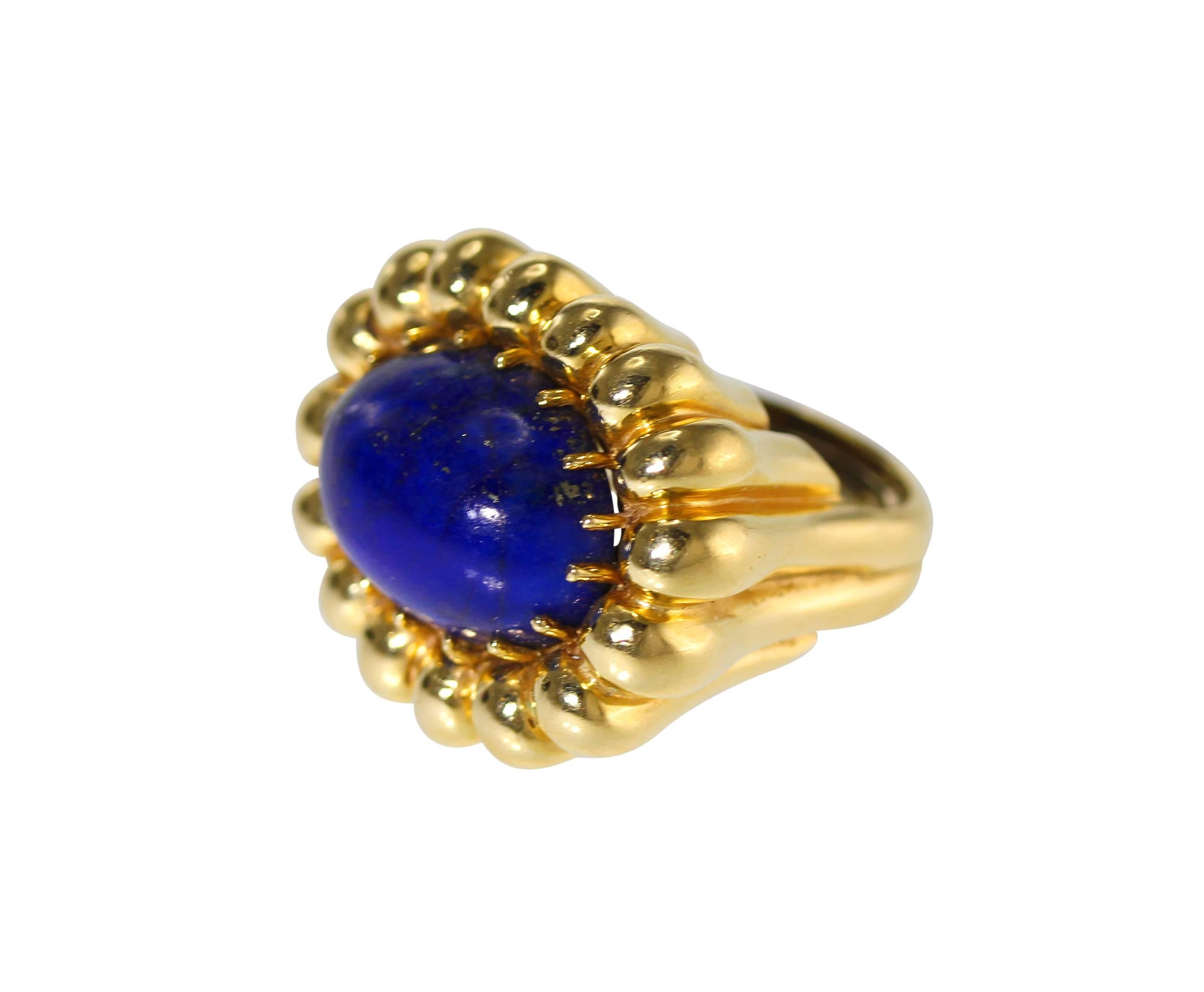 An 18 karat yellow gold and lapis lazuli ring, circa 1970, of fluted design set sideways in the center with a cabochon oval lapis lazuli measuring approximately 20.0 x 15.0 mm, size approximately 6 1/2, gross weight 26.2 grams. 
