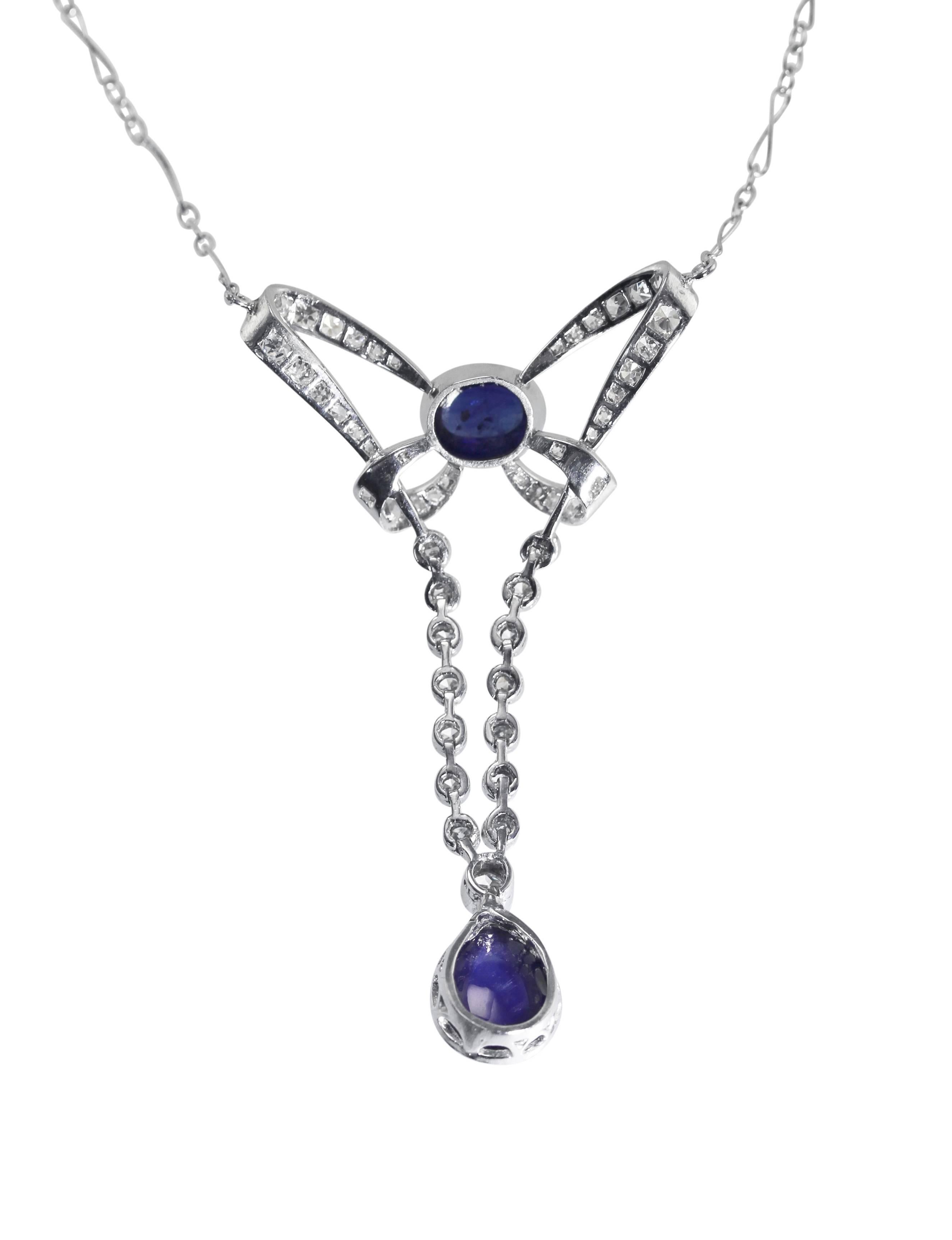 An Early 20th Century platinum, sapphire and diamond pendant-necklace, the articulated pendant designed as an ornate bow set at the top with a cabochon sapphire weighing approximately 1.50 carats, suspending a pendant set with a pear cabochon