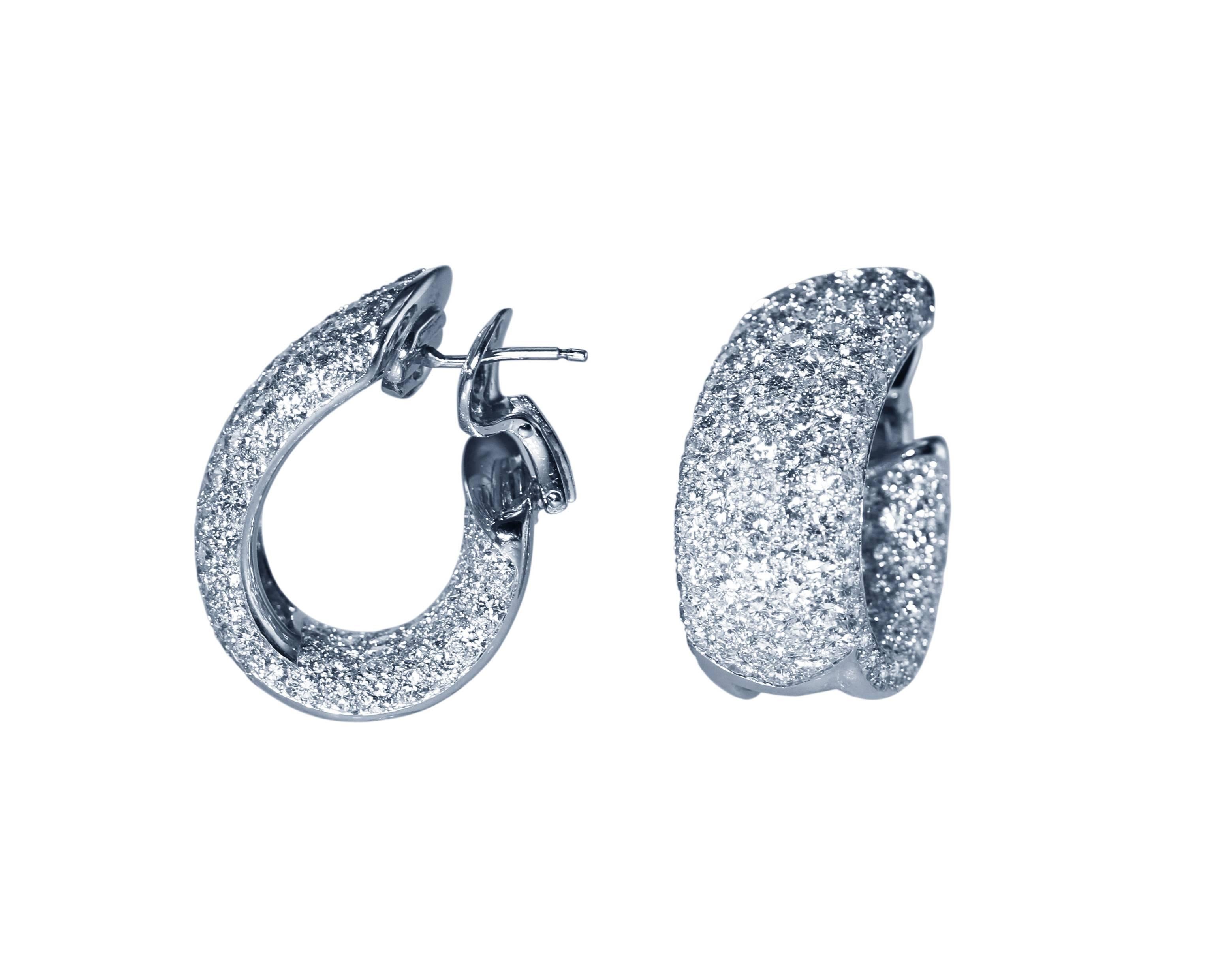 A pair of 18 karat white gold and diamond hoop earrings by Cartier, France, designed as stylized wide hoops pave-set with 288 round diamonds weighing approximately 20.00 carats, gross weight 29.6 grams, measuring 1 1/8 by 1/2 inch, signed Cartier,