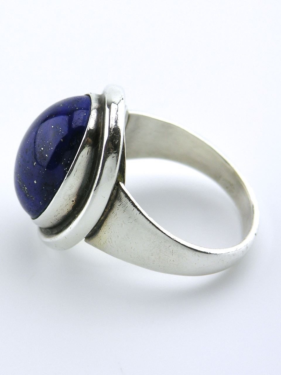 A large oval cabochon of lapis bezel set above a plain wire rim. 

- Marked with post 1945 marks for Georg Jensen of Copenhagen
- Design number 46A by Harald Nielsen
- Current size T (USA 9 5/8) Can be resized if required