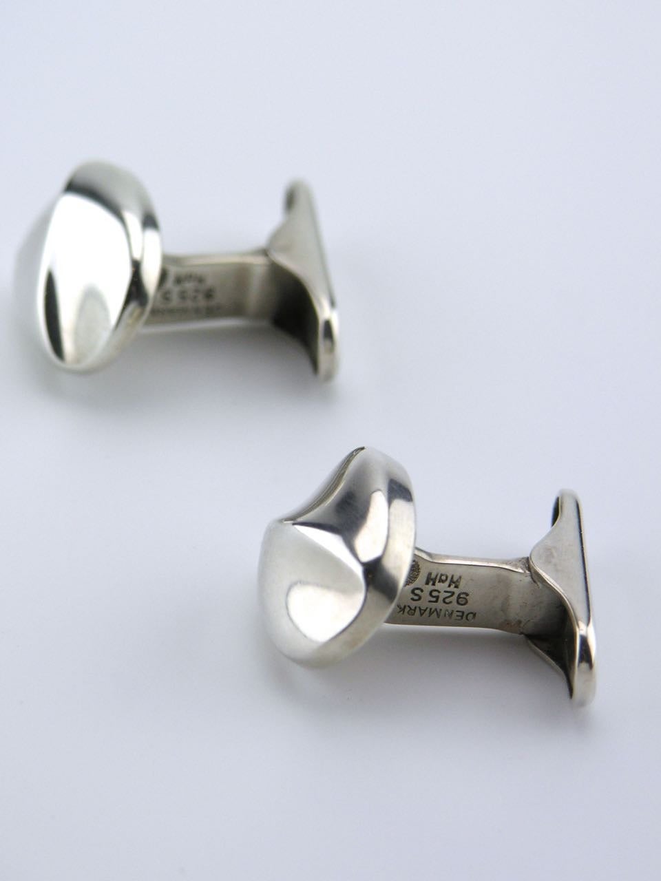 Amorphic cushion shaped cufflinks with a curved diagonal ridge on an arched sprung lever back. 

Marked HaH for Hans Hansen for Georg Jensen of Copenhangen.