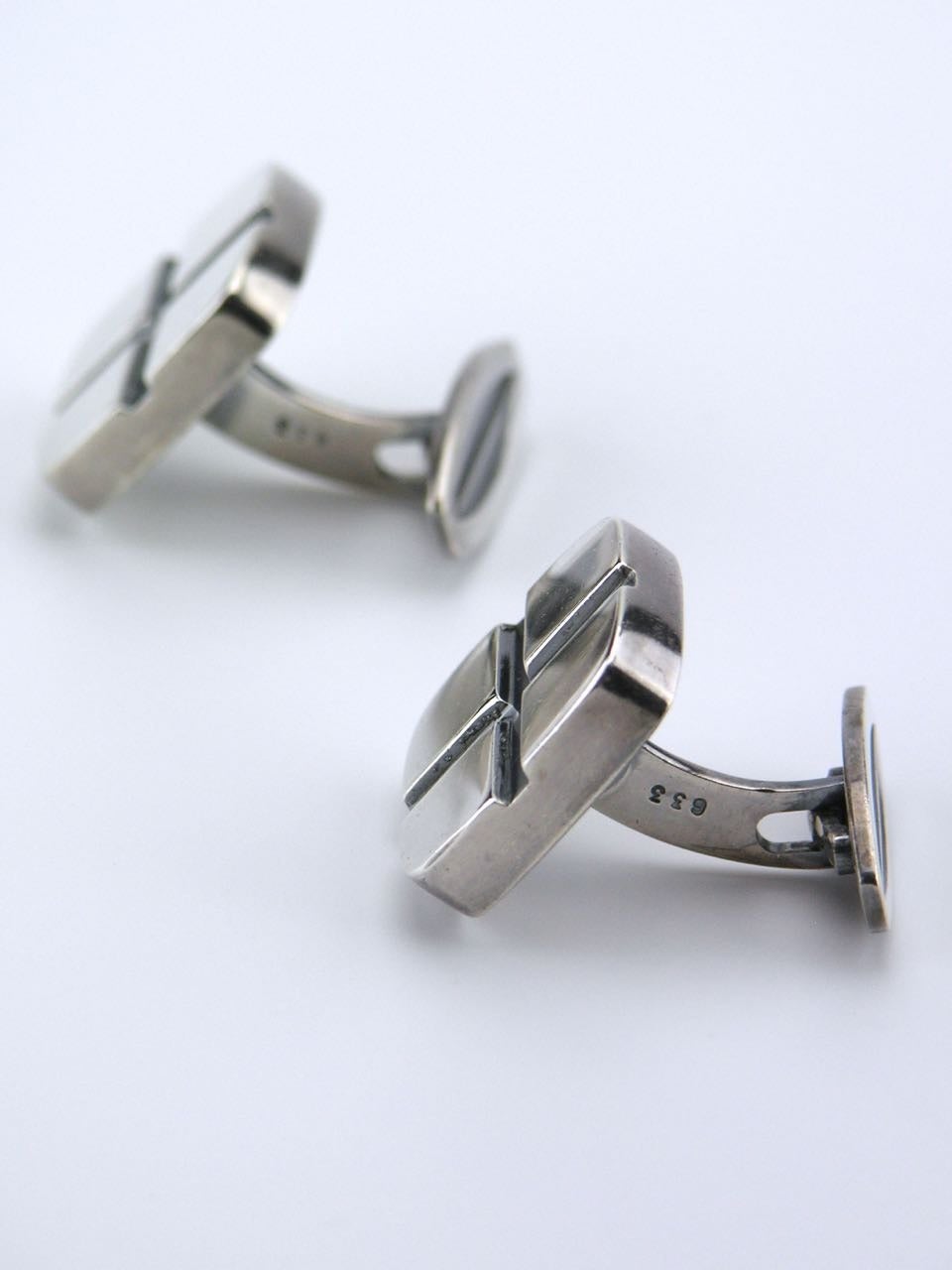 Rounded square tablet cufflinks with an insicised oxidised cross quartering the face. 

Marked for Hans Hansen of Kolding.