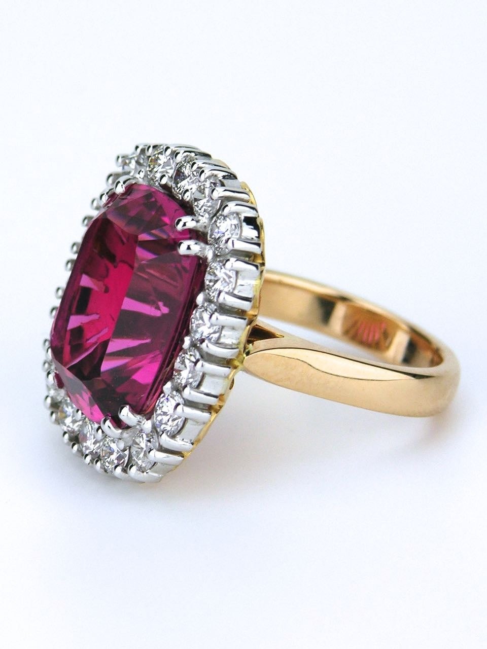An exceptional tourmaline and diamond cluster ring consisting of a stunning, finest quality, intense pink tourmaline of very good clarity and excellent cut, four claw set in 18ct white gold, on 18ct light rose gold gallery and shank, within a border