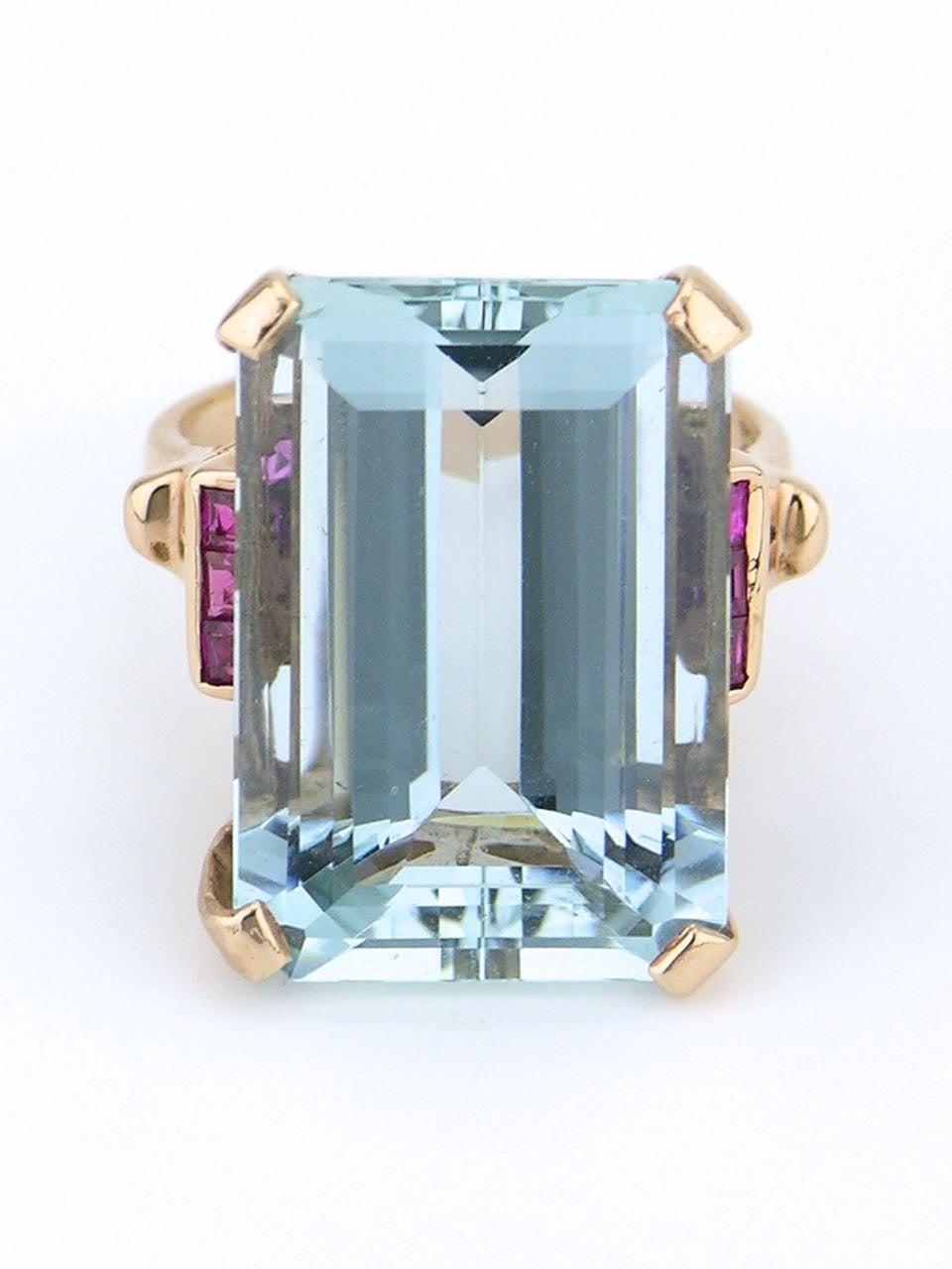 A large emerald cut aquamarine of 23.75cts with three square cut rubies on each side set in 14ct rose gold 

- aquamarine good clarity, good cut, light greyish blue 
- total weight  10.95grms 
- dimensions of face 22mm x 15mm 
- currently size