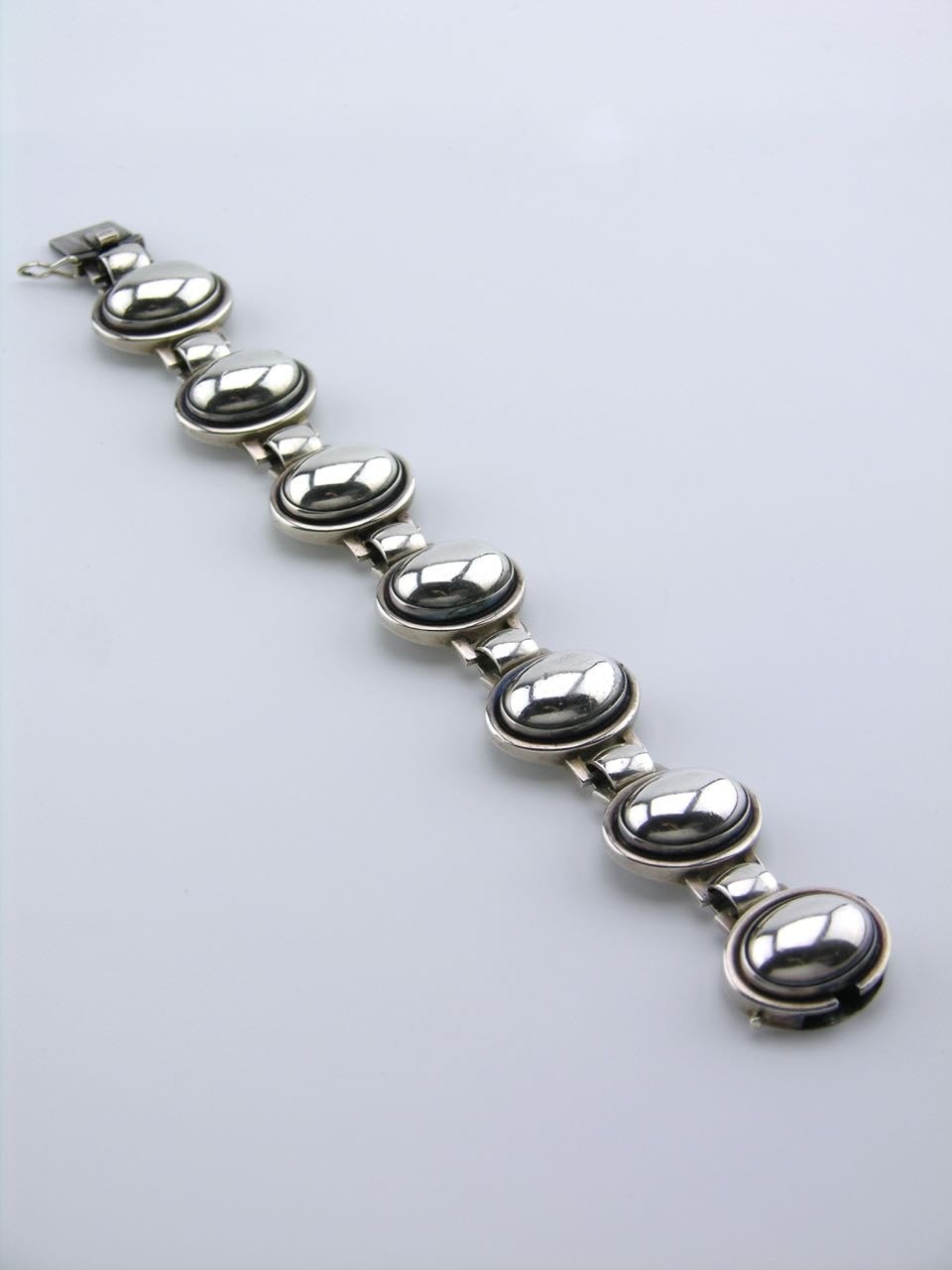 A very rare bracelet of 7 panels of an oval silver cabochon bezel set in a stepped setting with rectangular lugs and a wide domed link between. 

- marked with post 1945 marks for Georg Jensen of Copenhagen and design number 52 designed by Harald