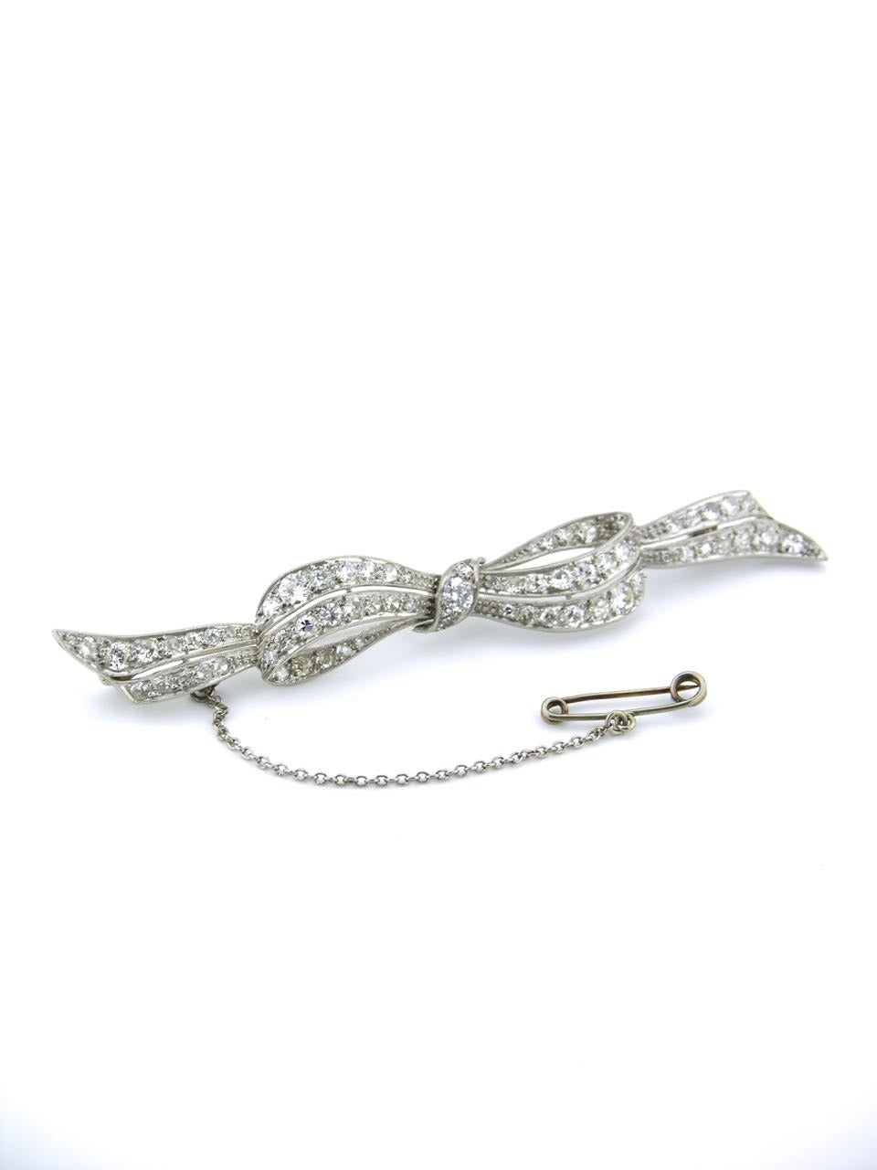 A platinum and diamond Art Deco bow brooch - a slim line design of a three dimensional platinum bow set with 69 diamonds with a rollover clasp to the pin at the back and an additional safety chain and pin 

- total diamond weight approx 2.80ct G-J