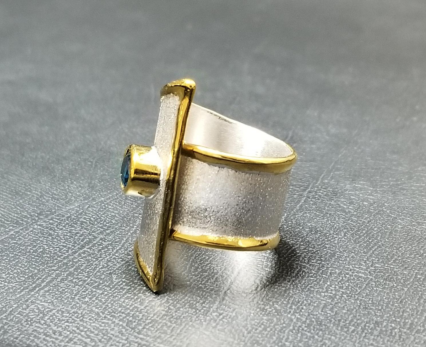 Presenting Yianni Creations Midas Collection 100% handmade artisan ring from fine silver 950 purity plated with palladium features 1.60 Carat oval cut London blue topaz. Liquid edges are decorated with a thick overlay of 24 Karat yellow gold. This