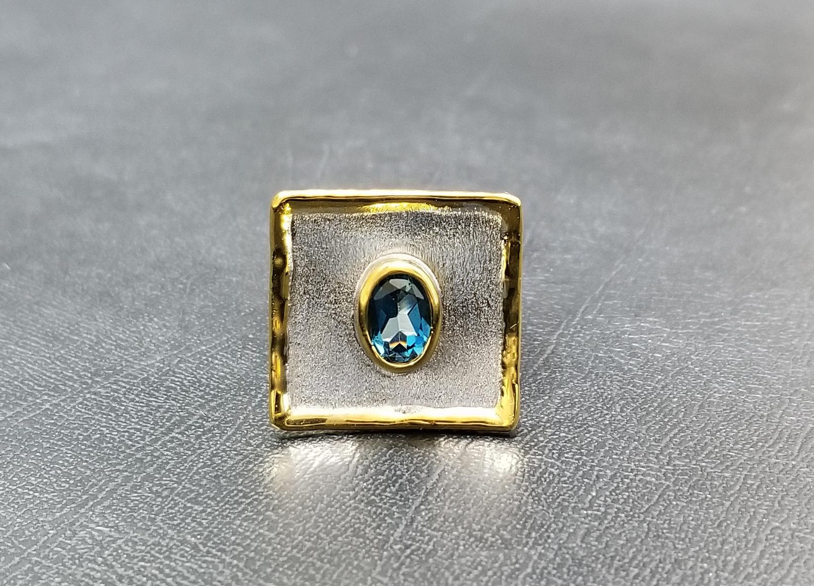 This is Yianni Creations Midas Collection 100% handmade artisan ring from fine silver with palladium plate to resist elements.  This geometric-shaped ring features a 1.60 Carat oval-shape London blue topaz complemented by unique liquid edges plated