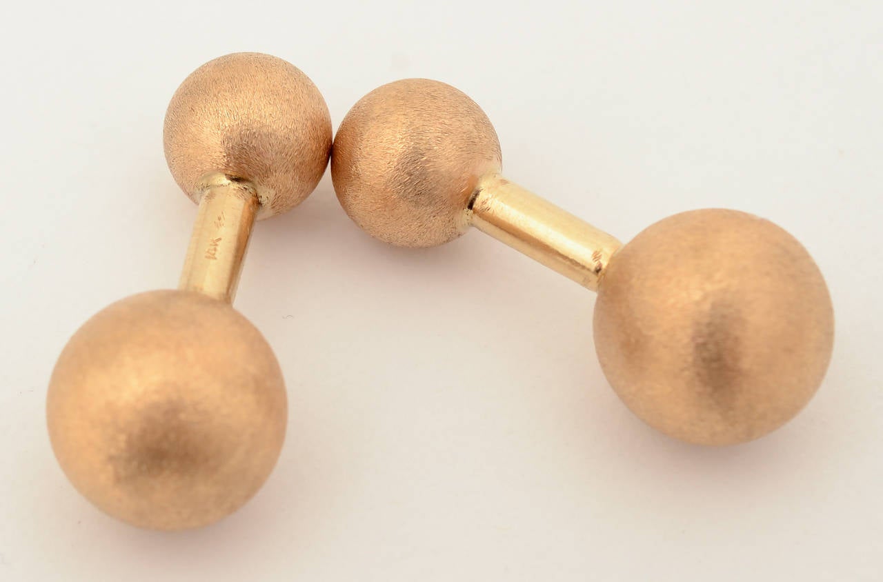 Fourteen karat gold barbell cufflinks by Tiffany. They have a soft brushed finish. The larger ball is approximately 12 mm in diameter and the smaller is about 8mm. Length is 1 1/8