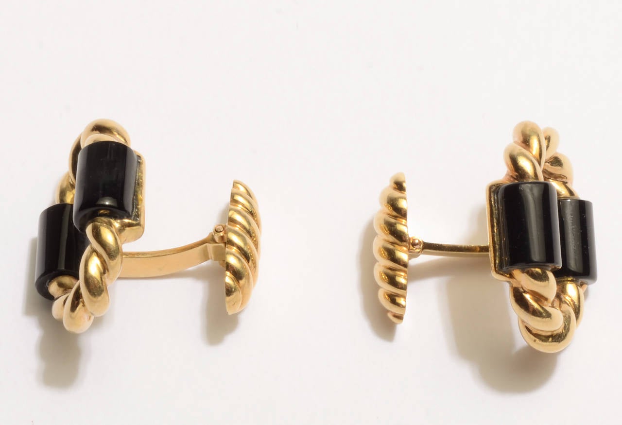 Elegant cufflinks of black onyx and twisted gold. The backs are oval shaped with a diagonal ribbed design. They are hinged to make it easy them  insert. French hallmarks; 18 karat gold.