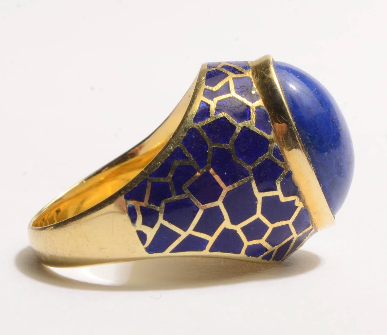 A central oval lapis lazuli is surrounded by an irregular enamel work design in this 18 karat gold ring.

It is size 6 1/2 but can easily be sized up or down.
Can be worn equally well by a man or woman.
