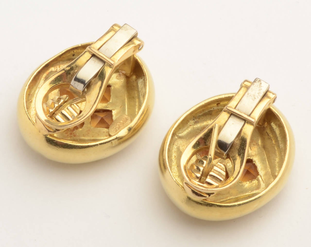 Four square citrines are set on point in these 18 karat oval earrings. The stones are richly honey colored.  The gold surround is nicely curved to give the effect of considerable volume. Backs are clips with collapsible posts. Marked JSE a maker