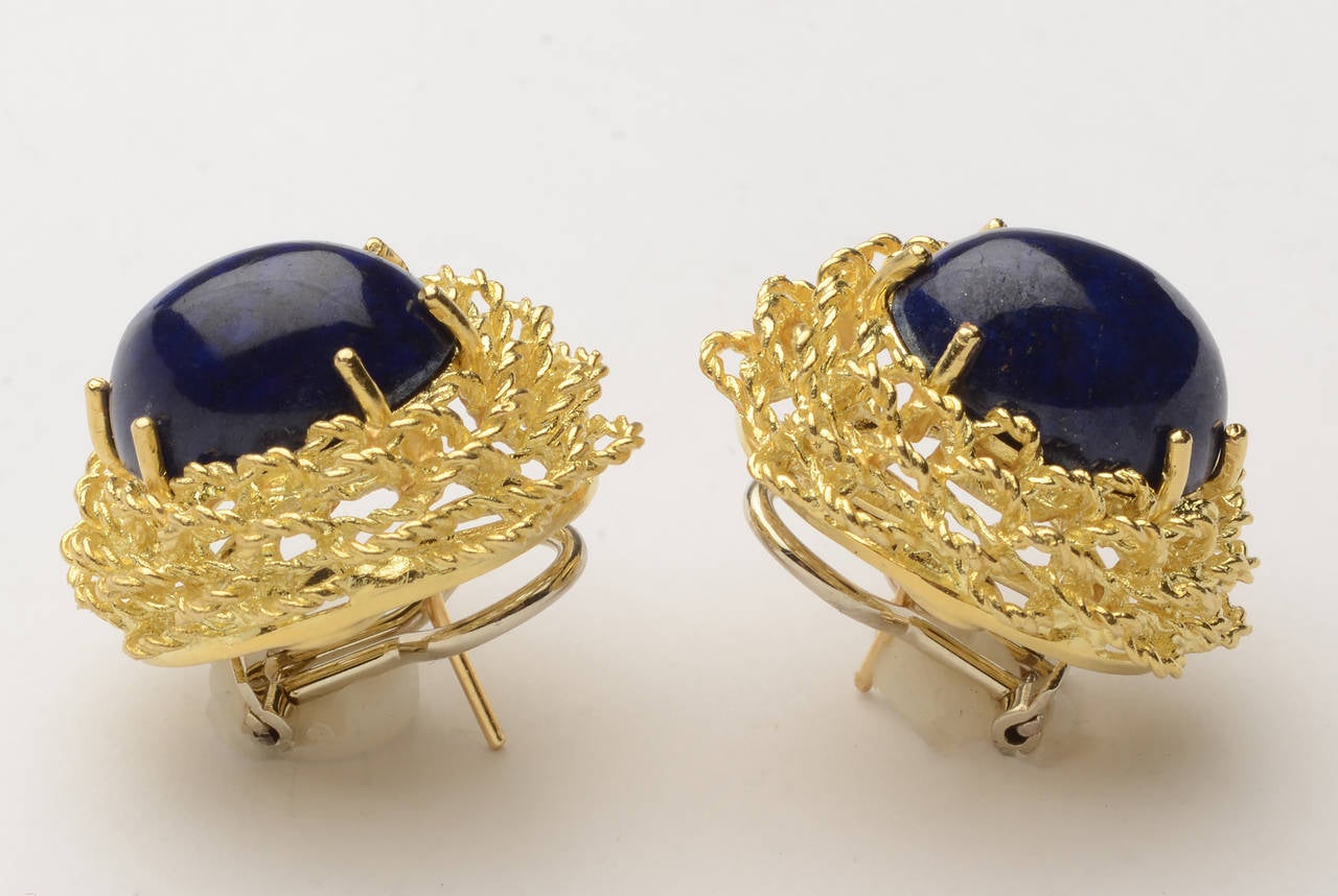 Beautifully made 18 karat gold earrings centered with oval lapis lazuli stones. Surrounding the stones are three tiers of braided gold circles  giving something of a lacey effect. There is a maker's mark that is not legible to me.