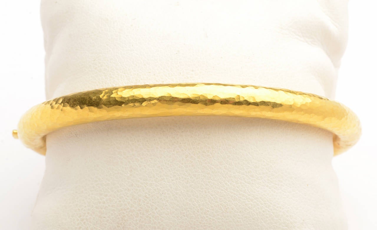 Classic hammered gold bangle bracelet made of 22 karat gold. The inside diameter is 2 7/16" and 2 13/16" to the outside diameter. It is 1/4" high. The bracelet is signed MMA which may refer to the Metropolitan Museum of Art. The