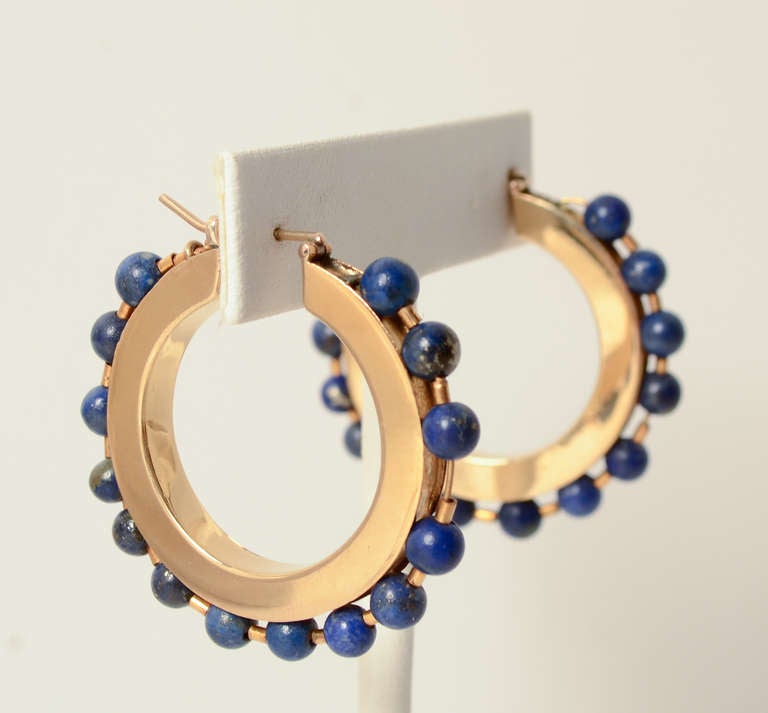 Large hoop earrings surrounded with beads of lapis lazuli. The earrings are 18 karat. They measure 1 1/2