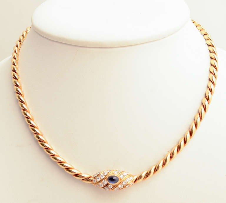 This rope twisted 18 karat gold necklace is centered with an oval medallion of a cabochon sapphire and 5 diagonal rows of diamonds.
The medallion measures 3/4" wide x 3/8" tall. The necklace is 15 1/2" in length. Signed VCA France.