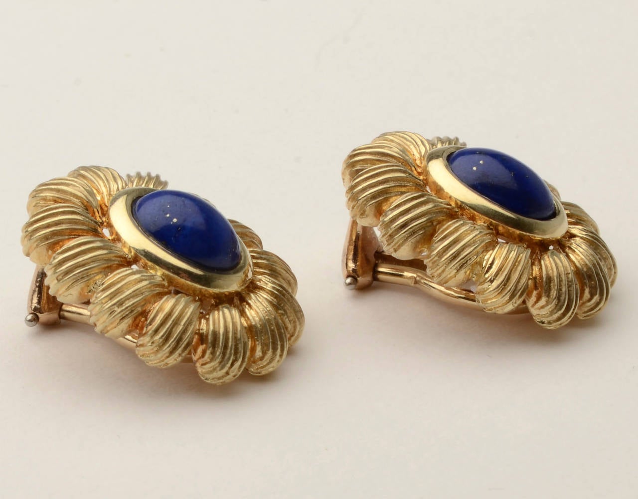 Des pierres ovales en lapis-lazuli forment de magnifiques centres pour ces boucles d'oreilles en forme de fleurs stylisées. Ils sont en or 14 carats et mesurent 3/4