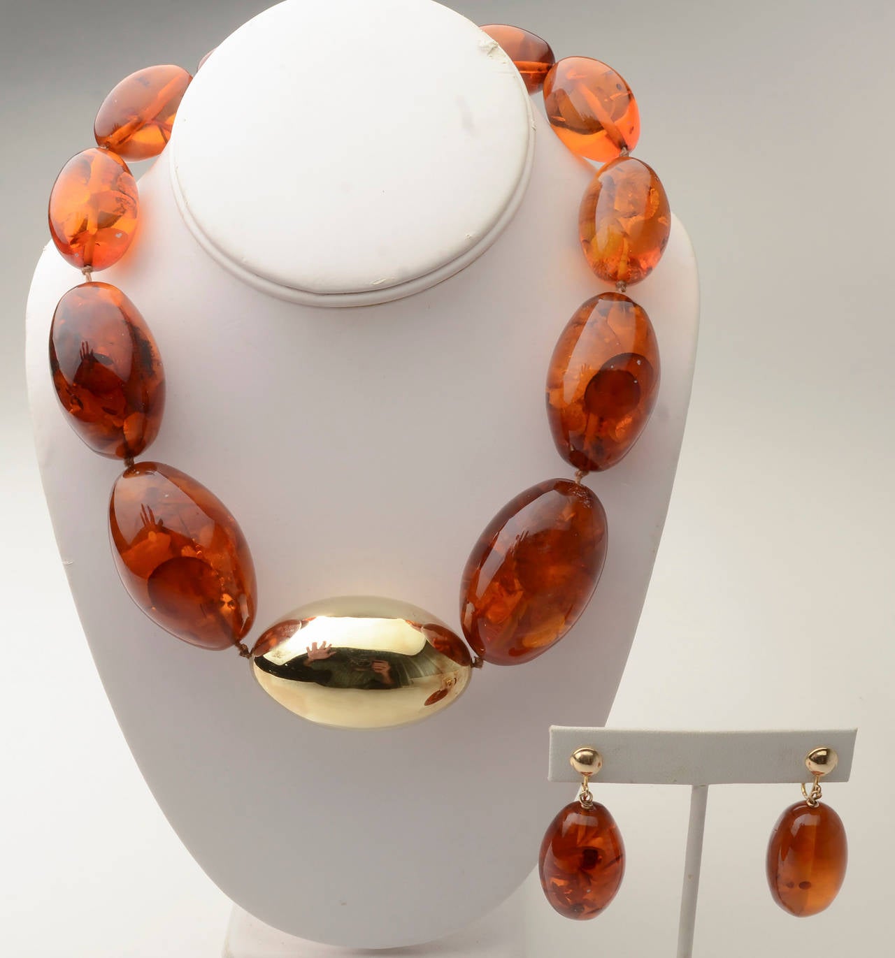 Unusual amber necklace with oval stones centered with a large 14 karat gold bead. The gold center measures 2 1/8