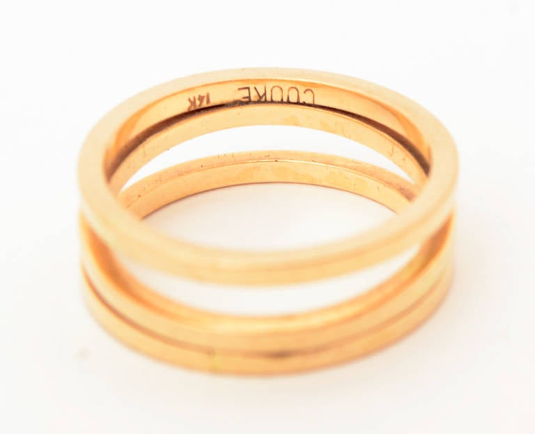 Cleverly made 14 karat gold ring that looks like three bands but is actually one continuous one. It has the streamlined, open and airy look characteristic of  modernist designer Betty Cooke's work. The ring is size 6 1/4. Cooke's work is in the