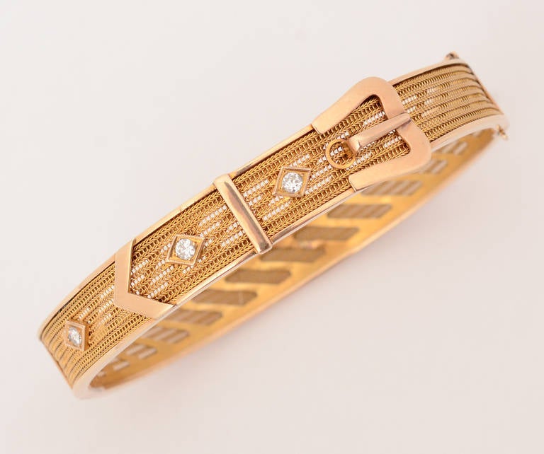 Finely detailed gold buckle bangle bracelet with 3 diamonds. The body of the bracelet is made of 7 rows of very fine rows of herringbone pattern. They are anchored with solid pieces of gold for the top and bottom edges as well as accenting the