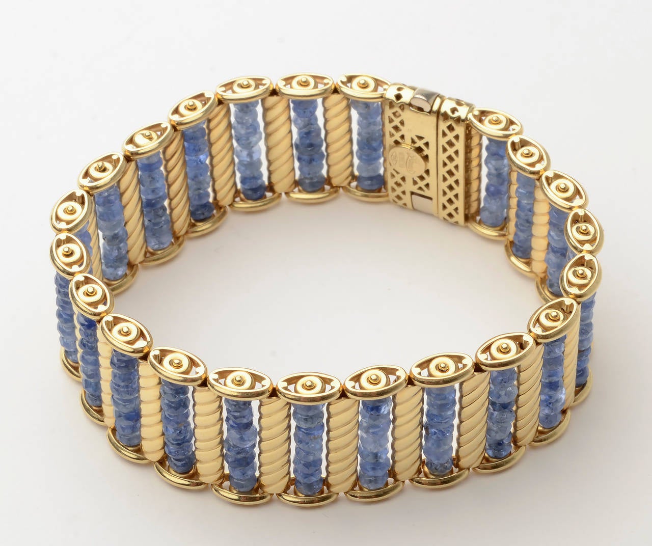 This unusual  bracelet by Zancan is made of oval sapphire beads surrounded by bars of gold with an incised diagonal design. It is beautifully constructed with nicely ornamented links on top and bottom. The bracelet is 18 karat gold. It measures 7