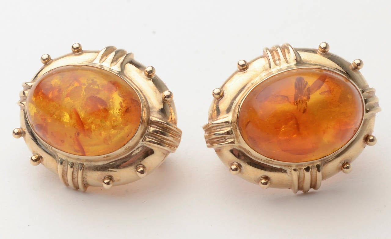 Thousands of years on earth have given these amber stones beautiful inclusions with a great deal of depth. They are set in 14 karat gold by Maz.

Raised banding and dots add to the dimensionality. The earrings are 1