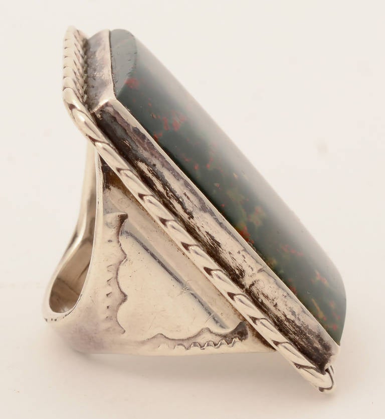 This ring by a Native American silversmith is the largest ring I have ever seen. The central stone is a beautifully mottled agate with a forest green ground and flecks of red. The stone measures 1 1/16