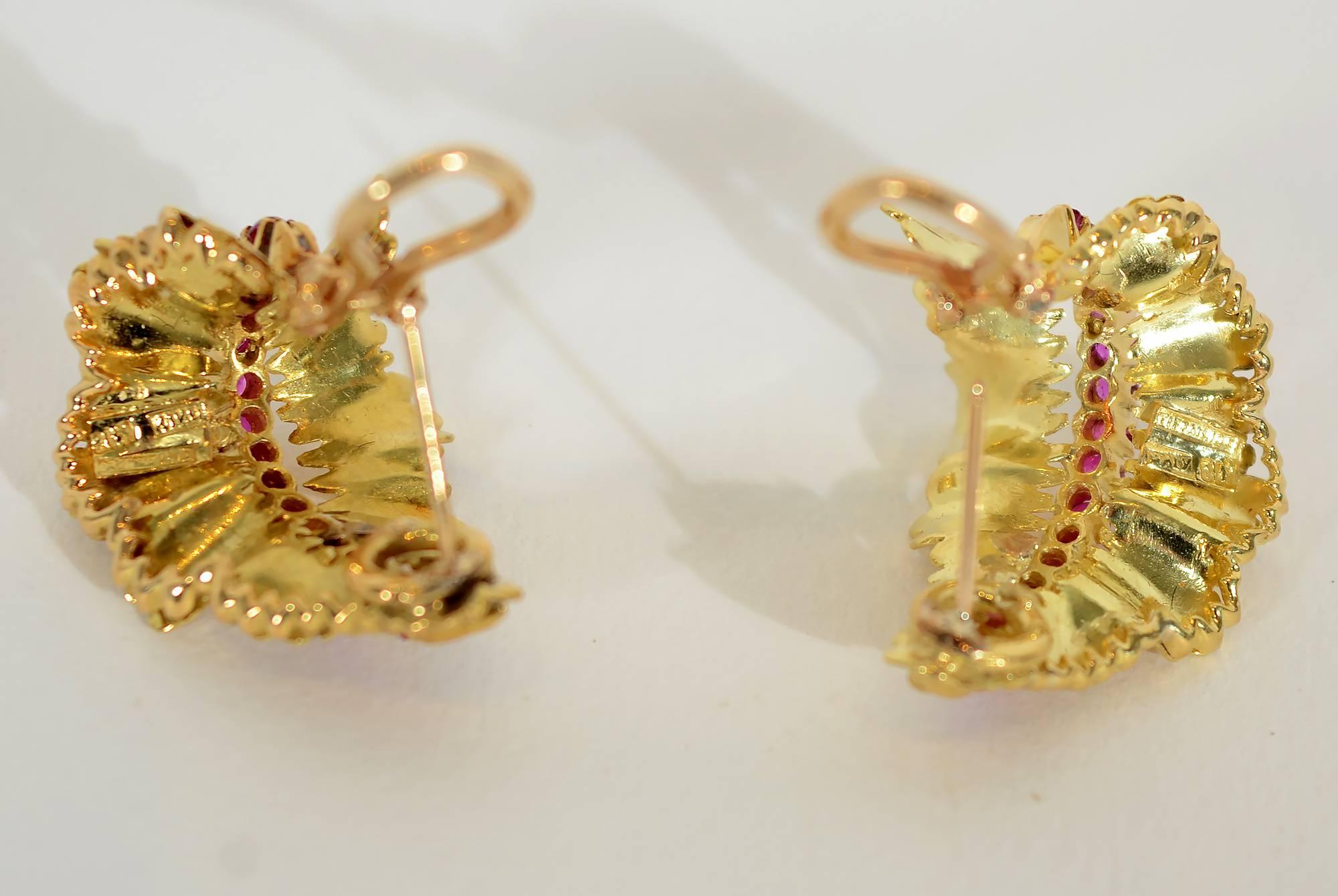 Intricately made gold with ruby earrings by Tiffany. The stylized leaves are made of undulating half hoops that are delicately incised with tiny, irregular lozenge shaped pieces and spines of rubies running vertically. The overall shape of the