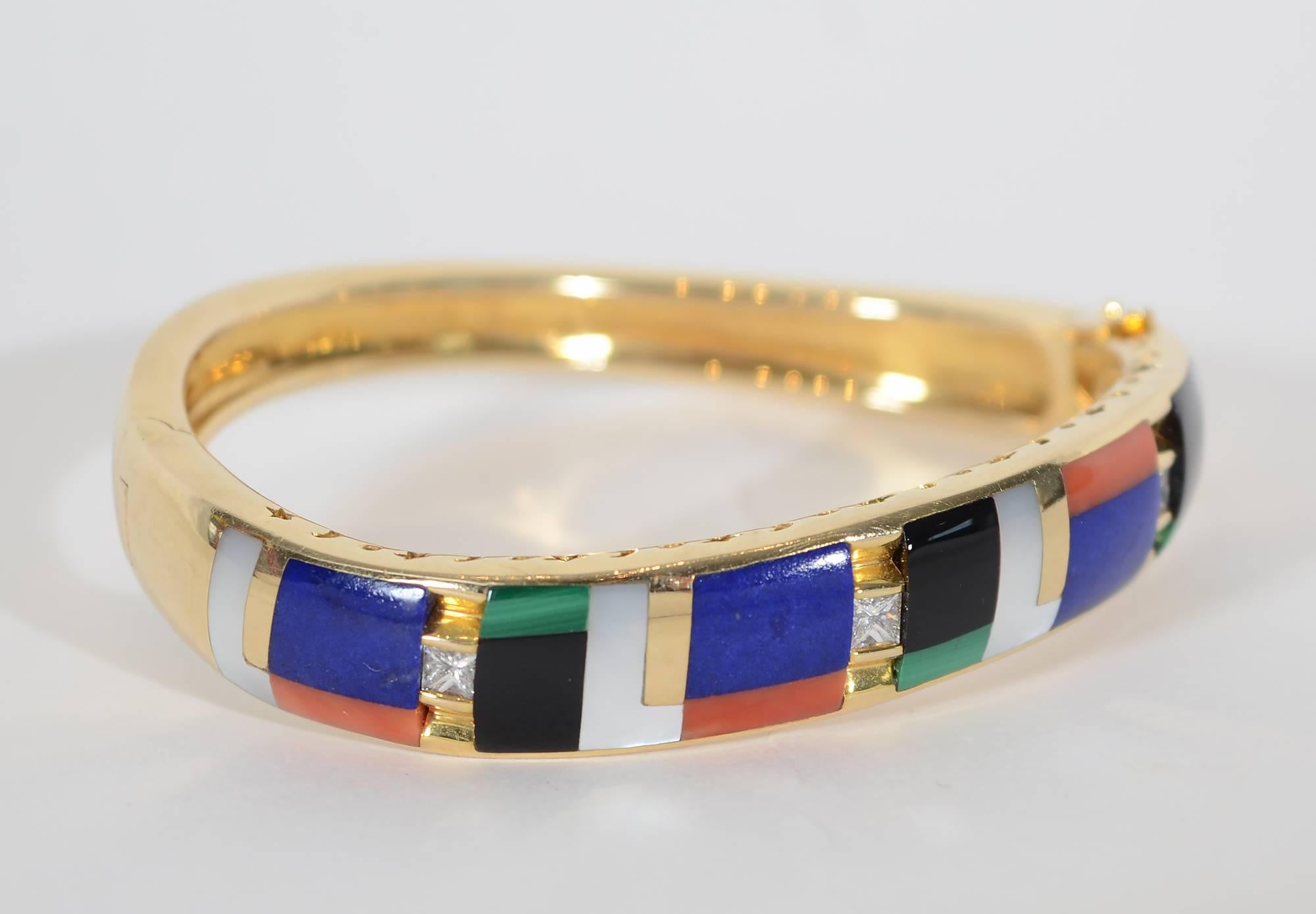 Squares and rectangles of a variety of stones are set on an angle in this bracelet by Asch Grossbardt. The stones include: black onyx; lapis lazuli; mother of pearl; malachite and coral. Three channel set diamonds are interspersed with the colored
