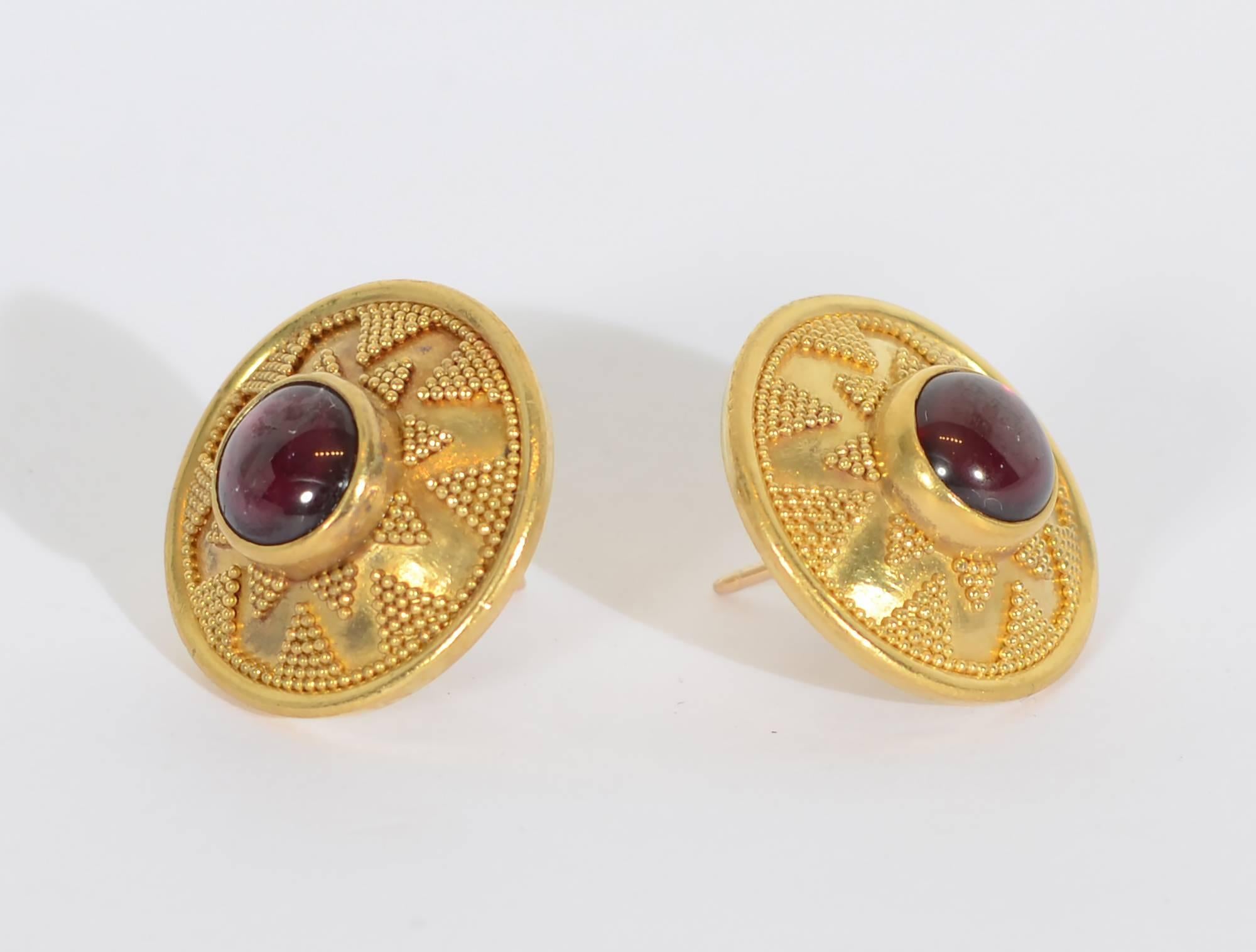 These ear studs demonstrate the finest of Etruscan gold work. Central cabochon garnets are the center of a star like design comprised of tiny, tiny balls. The earrings are 3/4
