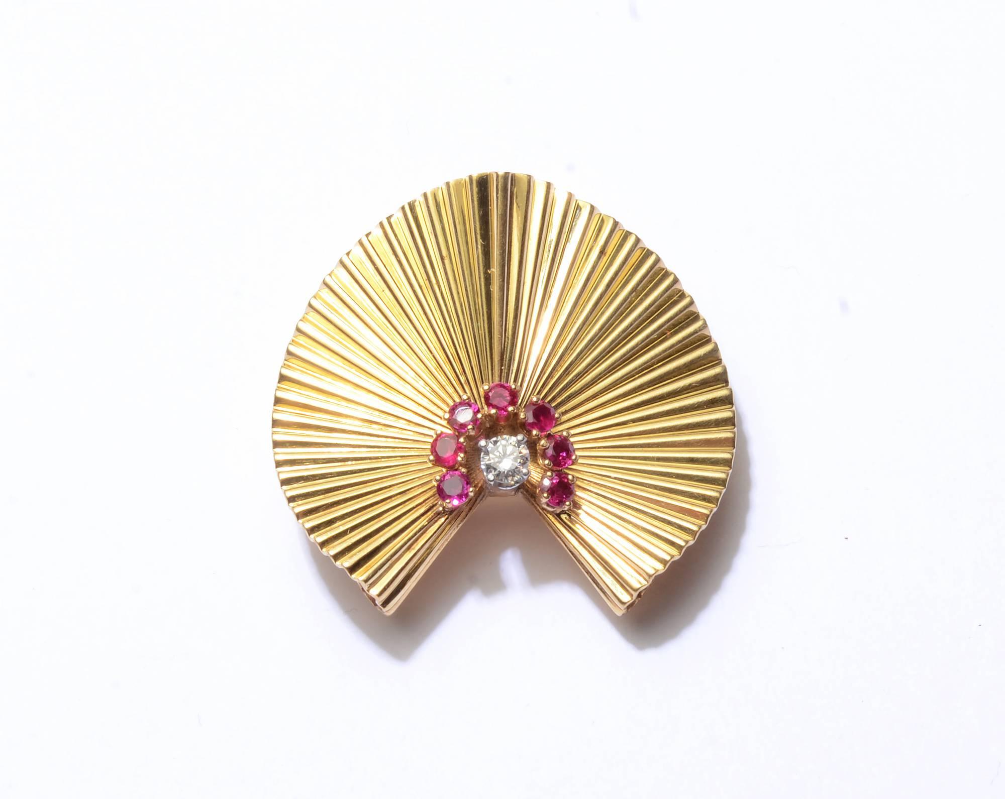 This gold and ruby  Retro brooch is especially graceful and versatile. The ribbed background is undulating giving a very 40's fans effect. The double pin stem indicates it is to be worn with the opening to the side but it is equally beautiful with