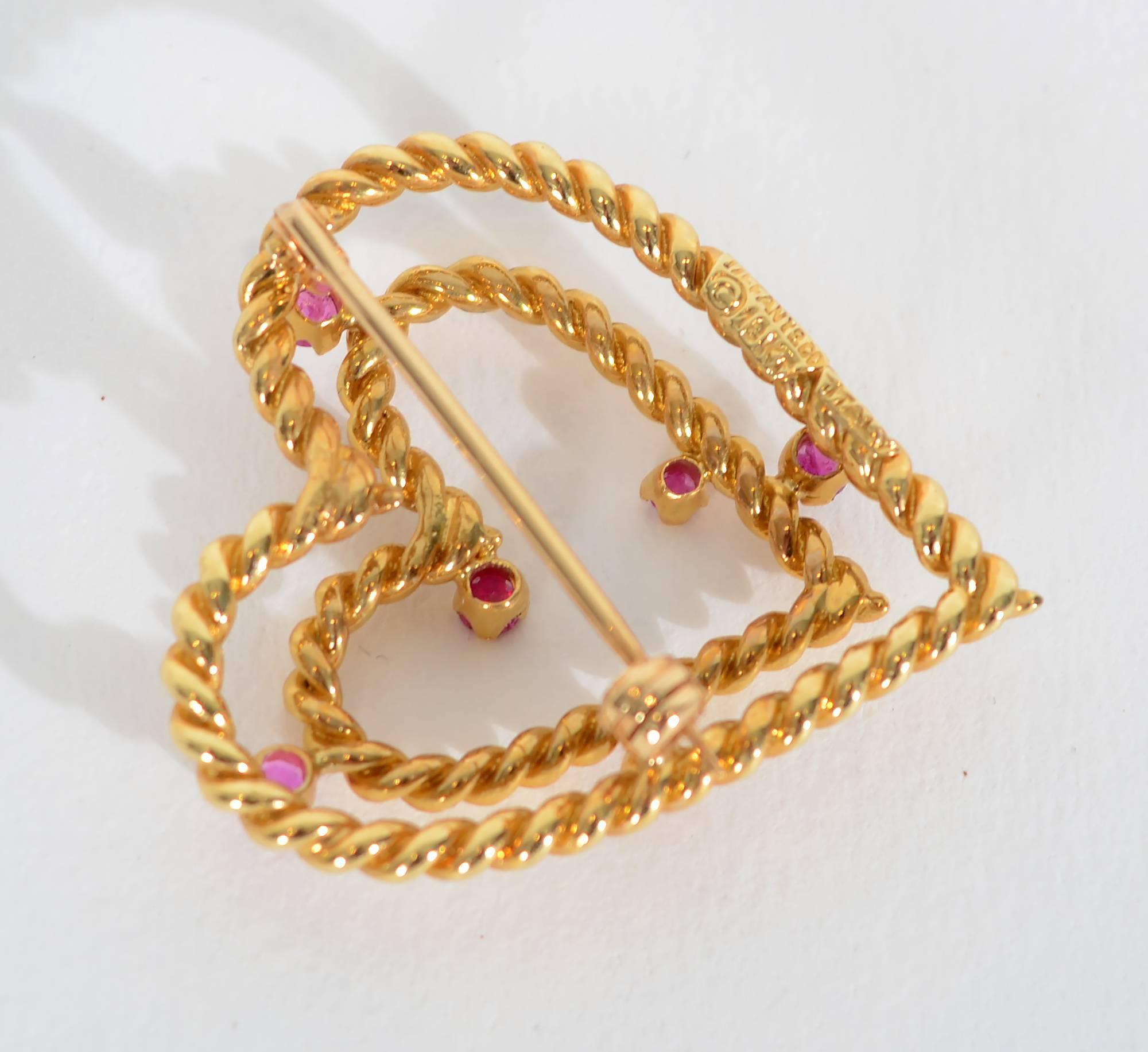 Double open heart brooch by Tiffany and Co. in 18 karat gold. Six rubies are interspersed throughout the twisted gold hearts. The open hearts make a good design as well as a meaningful symbol.