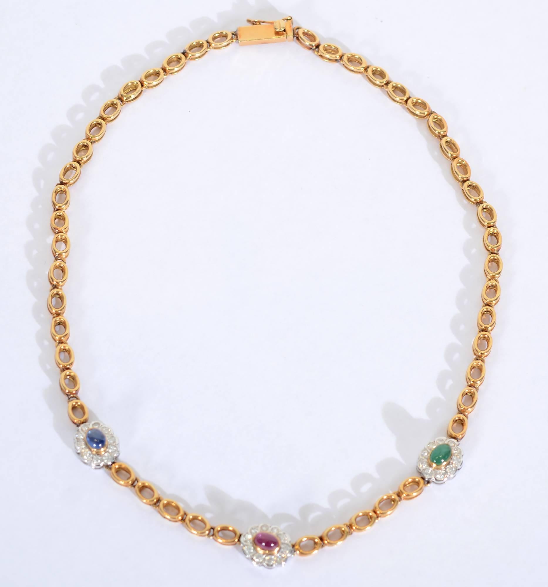 Custom made necklace with unusual links. Two ovals are set upon one another with a small space so the ovals do not touch created by a round link between them. The necklace is embellished with a sapphire; an emerald and a ruby in the center. Each of