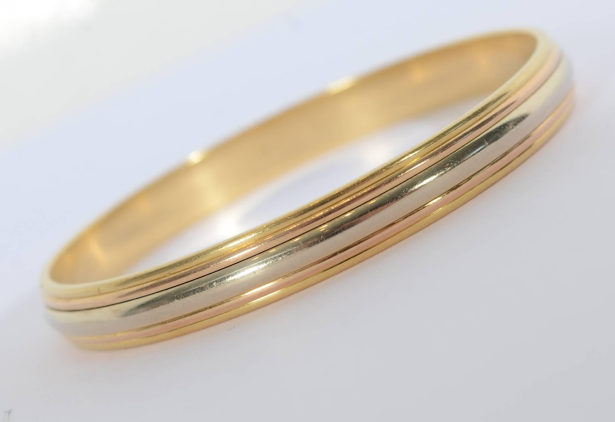 Cartier slip on 18 karat gold bangle bracelet in their signature tricolor gold. The pink gold is meant to represent love; the yellow for fidelity and the white for friendship. This lovely bangle bracelet measures 5/16